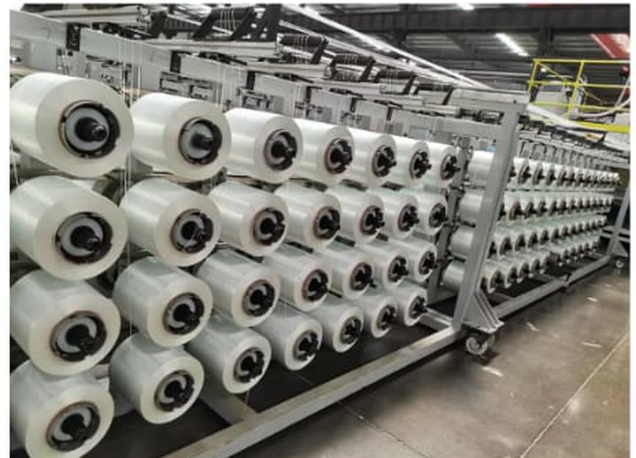 A dense rack of glass fibre spools feeding a production line