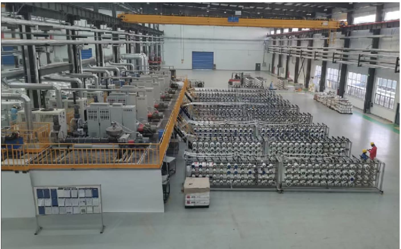 A UD tape plant floor seen from a gantry, extruders and creel racks running the length of the hall