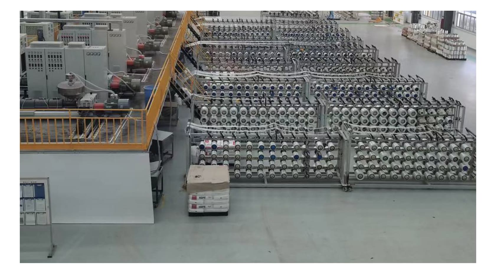 A UD tape production hall with long rows of glass fibre creels feeding extrusion lines